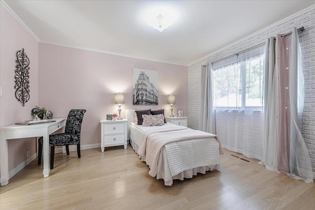 bedroom featuring ornamental molding, brick wall, access to outside, and light hardwood / wood-style flooring