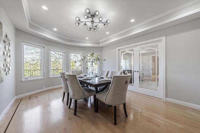 dining area featuring a tray ceiling, ornamental molding, light hardwood / wood-style floors, and french doors