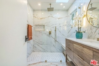 bathroom with vanity, tiled shower, and a skylight