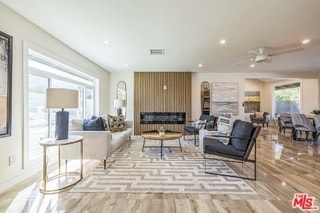 living room featuring ceiling fan, a large fireplace, and light hardwood / wood-style floors