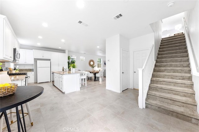 kitchen featuring a kitchen island with sink, a kitchen bar, white cabinets, and appliances with stainless steel finishes