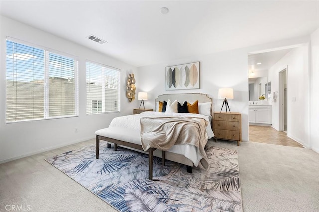 bedroom featuring light colored carpet and ensuite bath