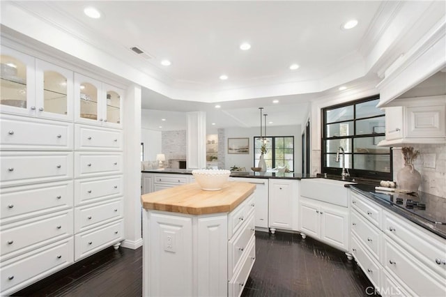 kitchen featuring wood counters, sink, a raised ceiling, a kitchen island, and white cabinets