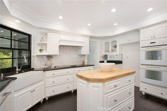 kitchen featuring a kitchen island, white cabinetry, sink, wooden counters, and white appliances