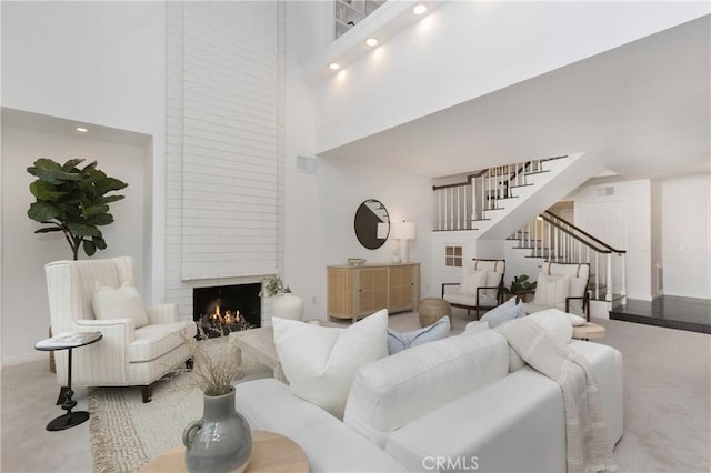 carpeted living room with a towering ceiling and a fireplace