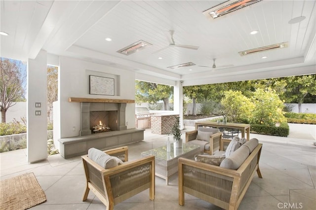 view of patio with ceiling fan, area for grilling, a grill, and an outdoor living space with a fireplace