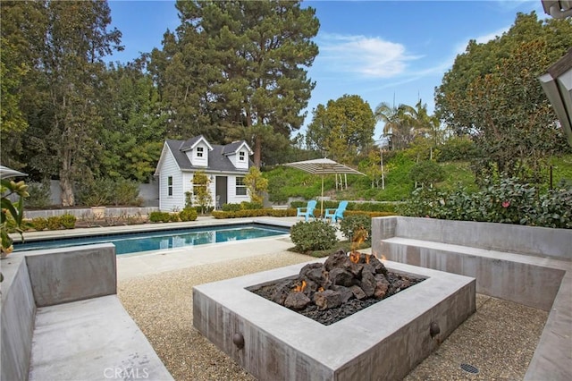 view of pool featuring an outdoor structure, a patio area, and a fire pit