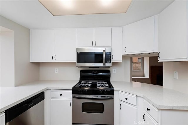 kitchen with appliances with stainless steel finishes, kitchen peninsula, and white cabinets