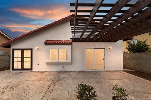 back house at dusk featuring a pergola and a patio area