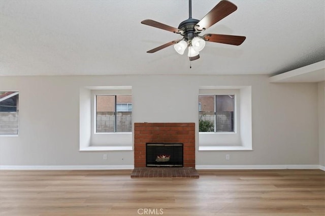 unfurnished living room featuring a fireplace, light hardwood / wood-style floors, and ceiling fan