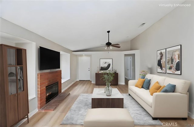 living room featuring a brick fireplace, lofted ceiling, ceiling fan, and light hardwood / wood-style flooring