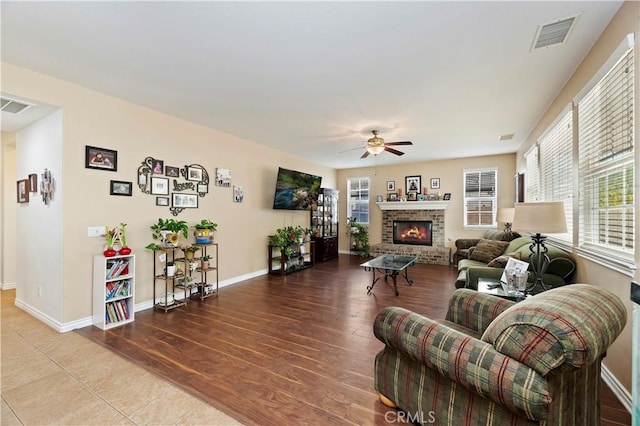 living room with a brick fireplace, hardwood / wood-style flooring, plenty of natural light, and ceiling fan