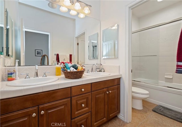 full bathroom with vanity, bath / shower combo with glass door, tile patterned floors, and toilet