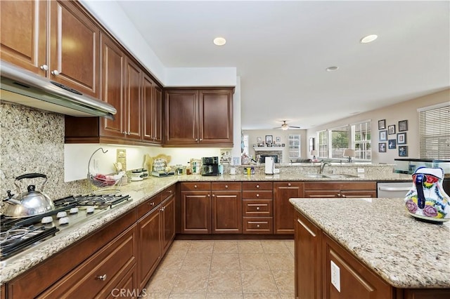 kitchen with stainless steel gas stovetop, ceiling fan, sink, and light stone counters