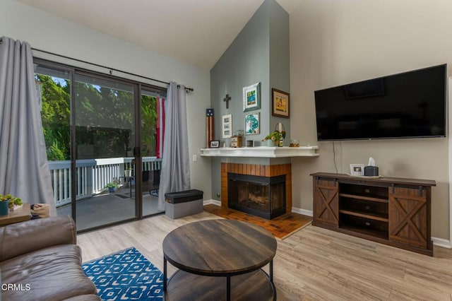 living room featuring a brick fireplace, light hardwood / wood-style flooring, and high vaulted ceiling