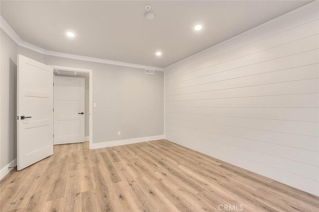 spare room featuring ornamental molding and light wood-type flooring