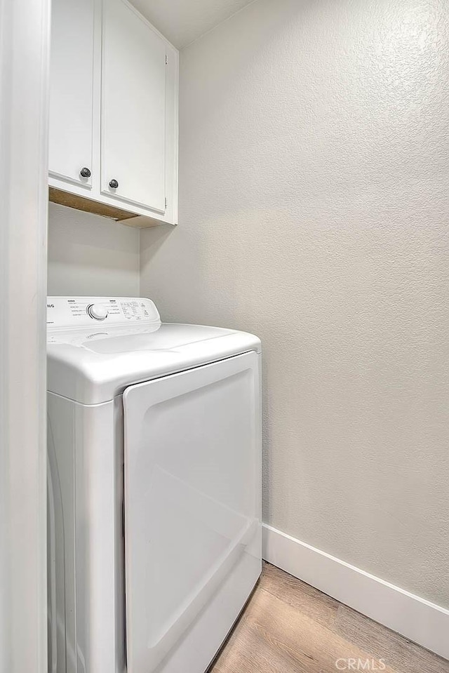 laundry area featuring cabinets, separate washer and dryer, and light hardwood / wood-style flooring