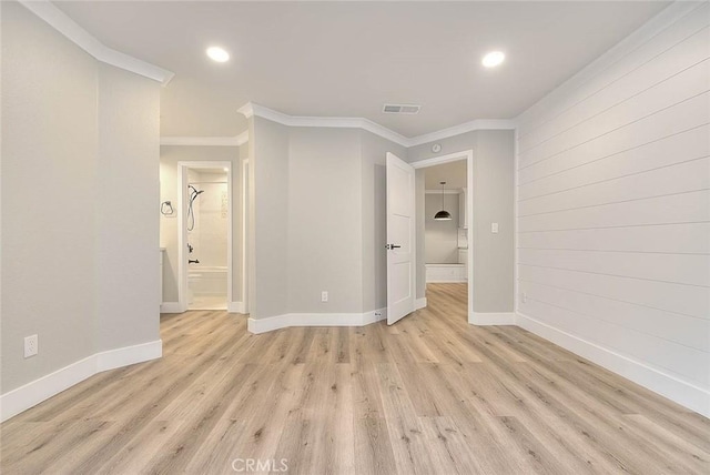 empty room with crown molding and light hardwood / wood-style flooring