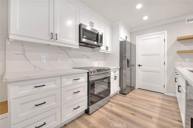 kitchen with appliances with stainless steel finishes, white cabinets, light stone counters, crown molding, and light wood-type flooring