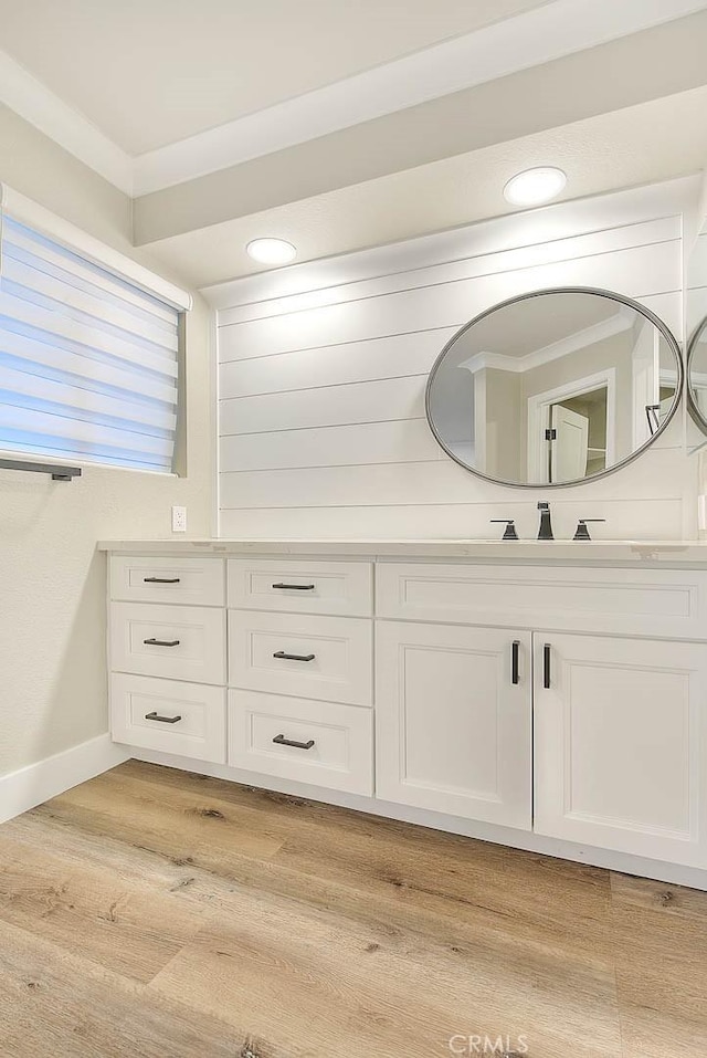 bathroom with crown molding, vanity, and hardwood / wood-style flooring