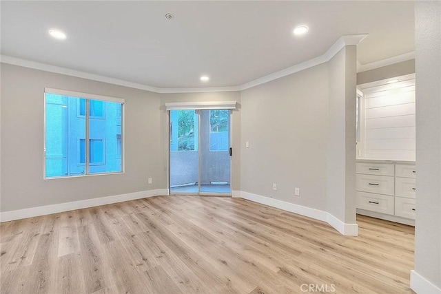 spare room featuring ornamental molding and light hardwood / wood-style floors