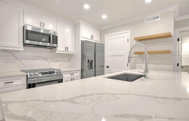 kitchen with stainless steel appliances, light stone countertops, sink, and white cabinets