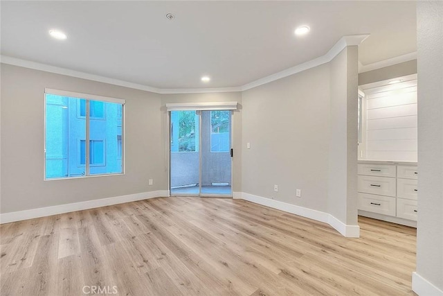 spare room featuring ornamental molding and light wood-type flooring