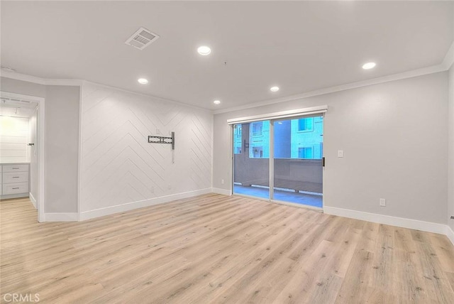 empty room with crown molding and light hardwood / wood-style floors