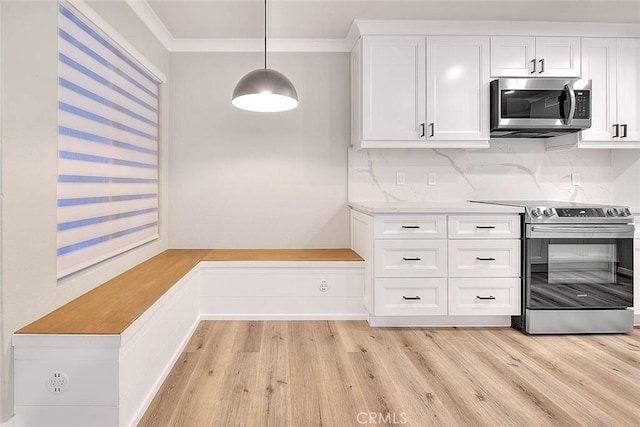 kitchen with hanging light fixtures, white cabinetry, appliances with stainless steel finishes, and crown molding