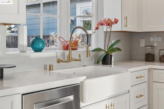 kitchen with white cabinets, dishwasher, sink, and backsplash