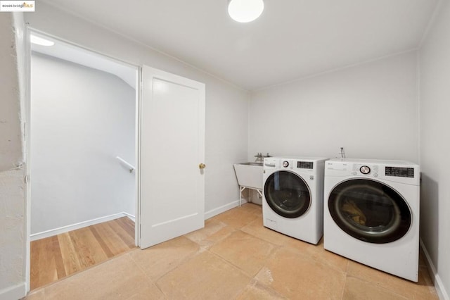 clothes washing area with washer and clothes dryer, sink, and light tile patterned floors