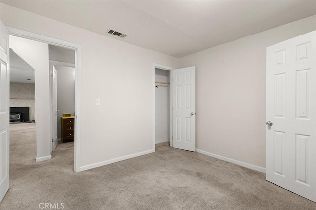 unfurnished bedroom featuring light colored carpet and a tile fireplace