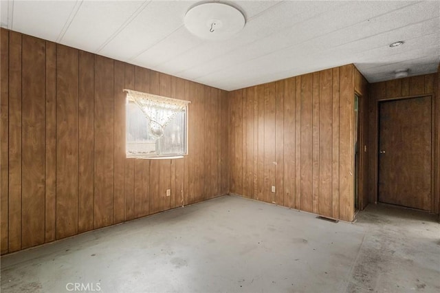 unfurnished room featuring wood walls