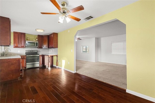 kitchen with appliances with stainless steel finishes, dark hardwood / wood-style floors, sink, decorative backsplash, and ceiling fan