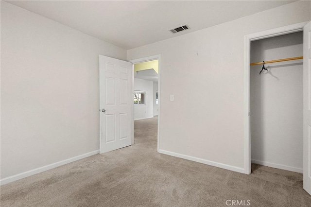 unfurnished bedroom featuring light carpet and a closet