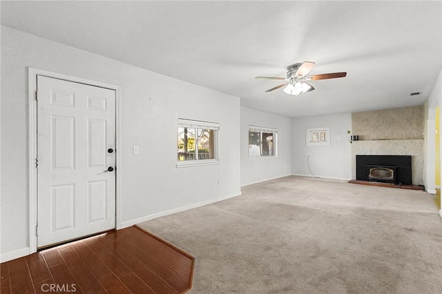 unfurnished living room featuring carpet, a large fireplace, and ceiling fan