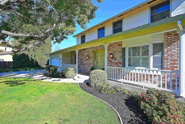 view of front of home with a garage, a front lawn, and covered porch