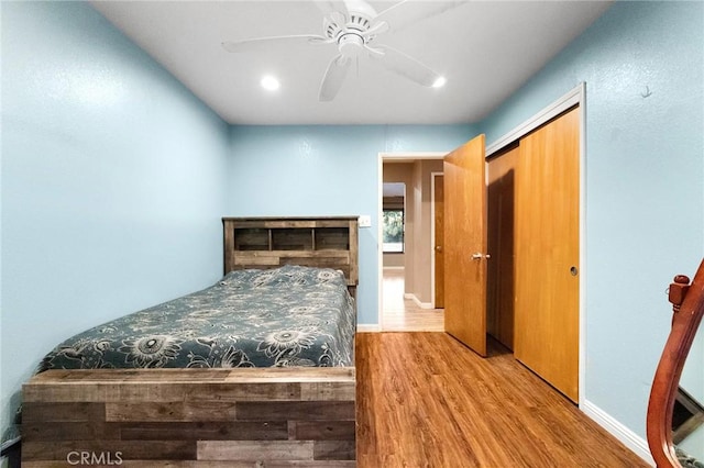 bedroom featuring a fireplace, a closet, ceiling fan, and light wood-type flooring