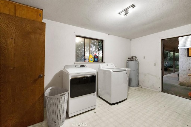 washroom featuring washer and clothes dryer, water heater, and a wealth of natural light