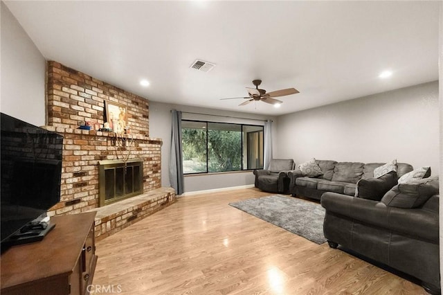 living room featuring a fireplace, light hardwood / wood-style floors, and ceiling fan