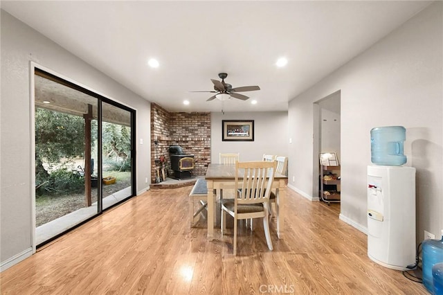 dining room featuring ceiling fan, a wood stove, and light wood-type flooring