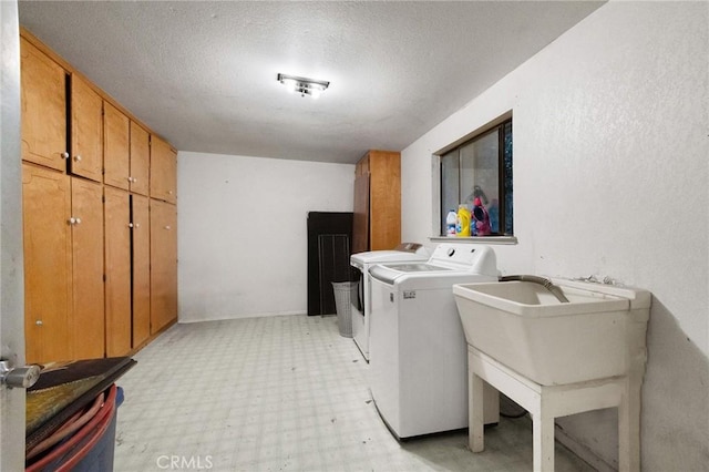 laundry room featuring washing machine and dryer, cabinets, and a textured ceiling