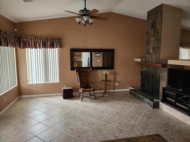 living area with ceiling fan, lofted ceiling, a fireplace, and light tile patterned floors