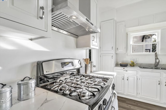 kitchen with sink, light stone countertops, gas stove, white cabinets, and wall chimney exhaust hood