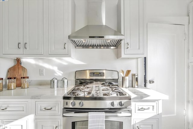 kitchen with light stone counters, range hood, gas stove, and white cabinets