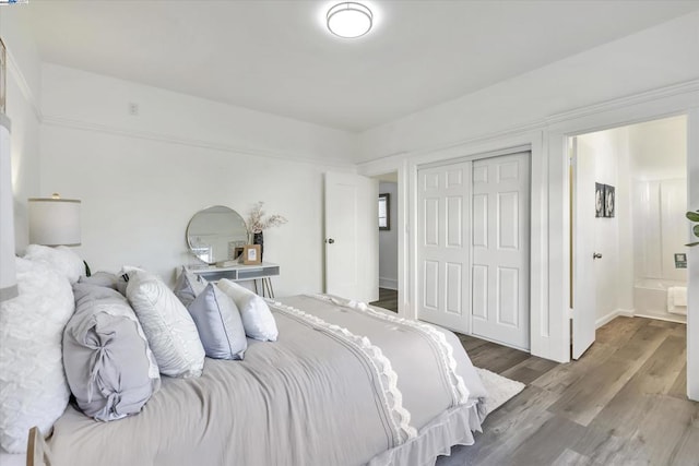 bedroom with hardwood / wood-style flooring, connected bathroom, and a closet