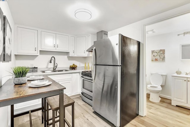 kitchen featuring stainless steel appliances, sink, light hardwood / wood-style flooring, and white cabinets