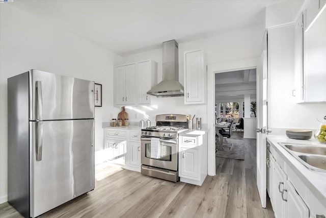 kitchen with white cabinetry, wall chimney range hood, light hardwood / wood-style flooring, and stainless steel appliances