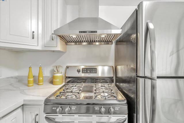 kitchen featuring white cabinetry, light stone counters, island range hood, and appliances with stainless steel finishes