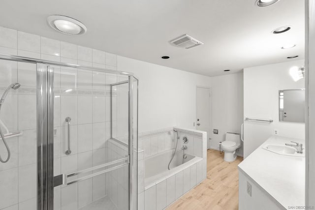 full bathroom with vanity, hardwood / wood-style flooring, shower with separate bathtub, and toilet